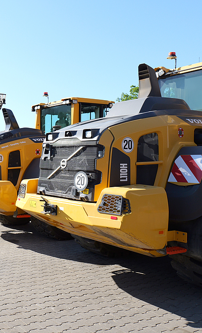Seitliche Ansicht vom Fuhrpark mit VOLVO CE Kompakt-Bau­maschinen und Traktoren