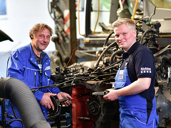 Mitarbeiter beim Achsölwechsel eines Traktors